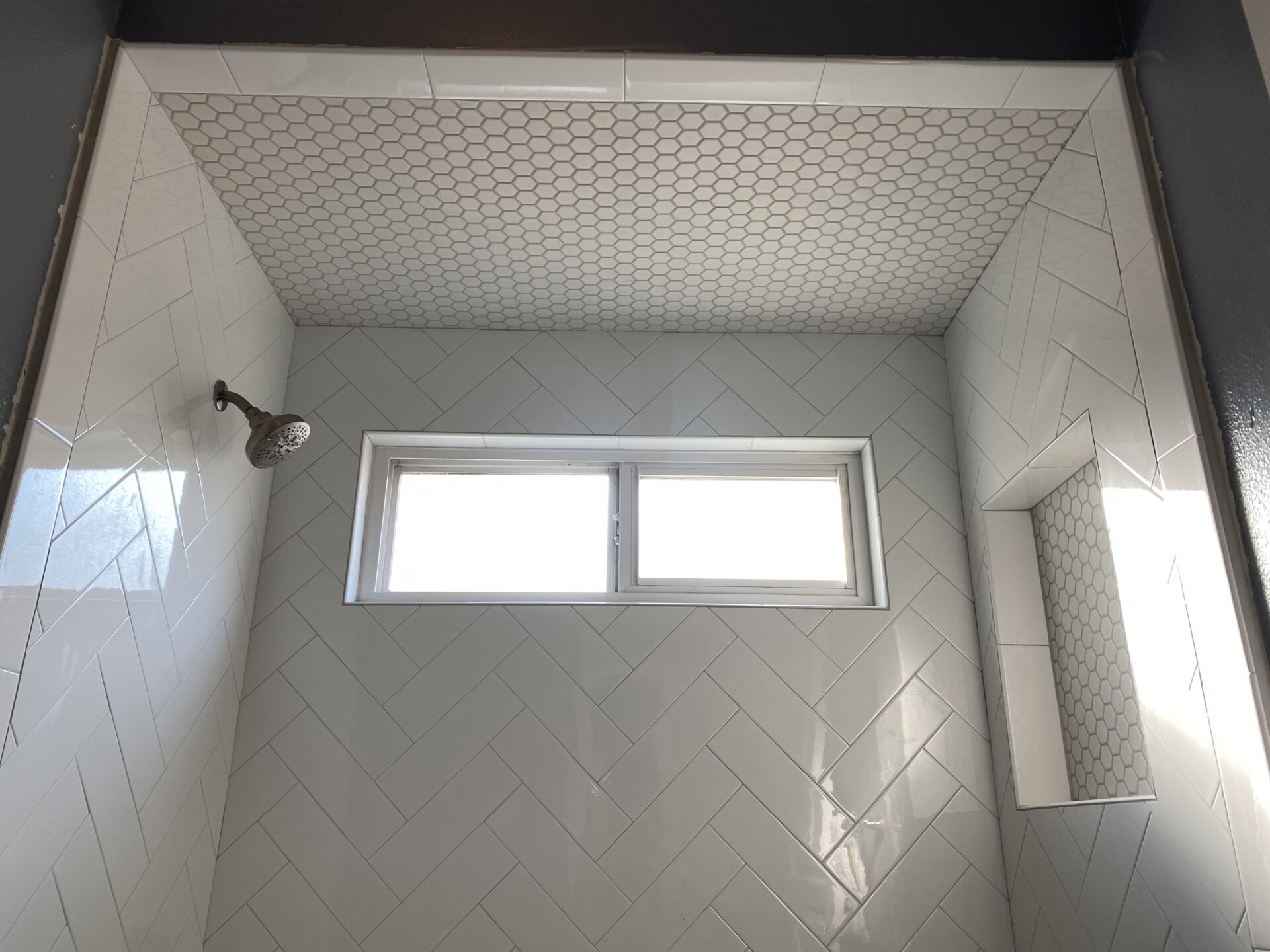 A bathroom with white tile and a window.